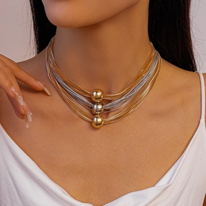 Detail of multi-layer gold and silver mixed chain necklace with three metallic beads