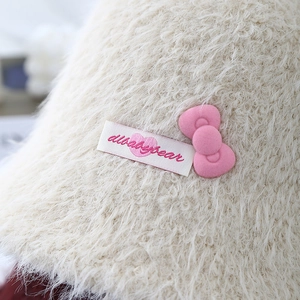 Cozy cream plush bucket hat featuring a sweet pink bow and knitted texture for winter