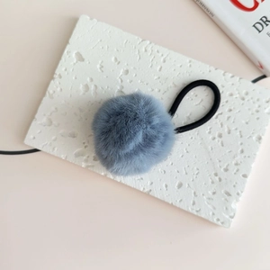 Close-up of fluffy grey faux fur pom pom hair tie with black high-elastic rubber band