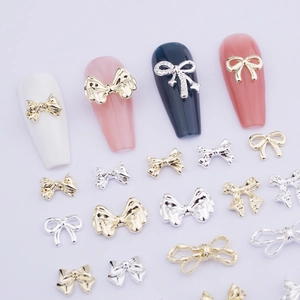 Detailed view of gold and silver metal bow nail charms with rhinestones on white background