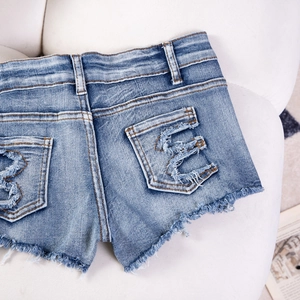 Dettaglio degli shorts in denim con bordi sfilacciati e tasca posteriore usurata