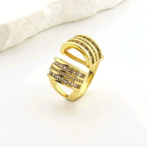 Close-up of a layered gold open ring with sparkling transparent gemstones on a stone base
