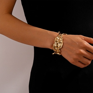 Detail of gold irregular crumpled lava texture open bangle on a model's wrist