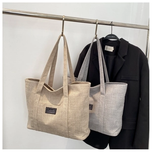 Close-up of woven tote bags in beige and silver grey with fashion labels hanging