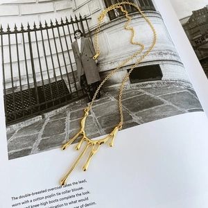 Artistic detail of gold liquid lava pendant necklace on fashion magazine background