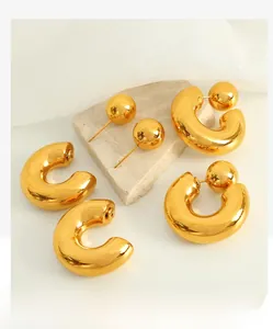 Detailed close-up of polished gold spherical C-shaped earrings on stone props