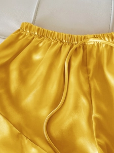 Détail du short de pyjama en satin jaune avec taille élastique et cordon de serrage