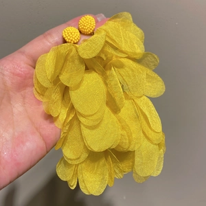 Close-up of bohemian vibrant yellow sunflower earrings made of woven raffia petals