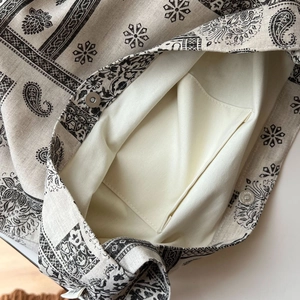 Close-up of canvas tote bag showing magnetic buckle and inner pocket with vintage print