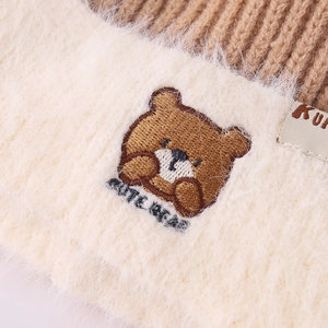 Detail of winter knit hat featuring bear embroidery and soft faux fur lining for kids