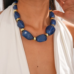 Close-up of irregular blue acrylic beads with golden spacers on a chunky necklace