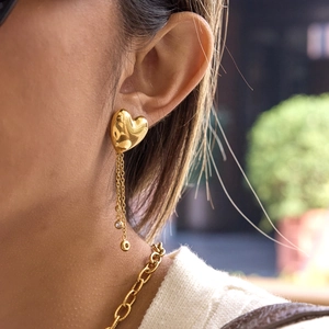 Elegant gold heart earrings with dangling tassel chains and rhinestones on a model