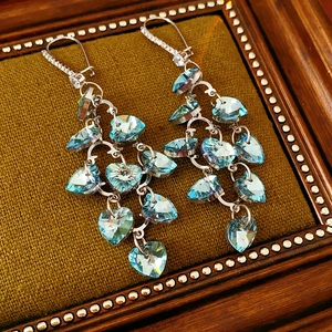 Detailed close-up of silver long tassel earrings with blue heart-shaped crystals