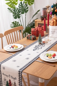 Modern Christmas table runner with snowflake prints and buffalo plaid edges in a festive setting