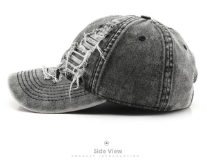Detailed close-up of distressed ripped details on washed grey denim baseball cap