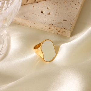 Dettaglio dell'intarsio di conchiglia bianca su un anello in acciaio inossidabile dorato