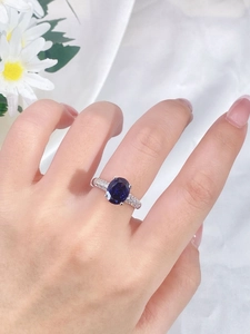 Detailed close-up of a blue oval gemstone ring with small diamonds on a model's hand