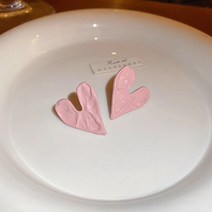 Pink heart stud earrings with vintage pleated texture displayed on a ceramic tray