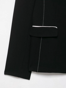Close-up of black textured blazer featuring white contrast piping and topstitching details