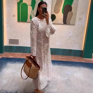 Elegant white lace long sleeve maxi dress with straw handbag in a stylish mirror selfie