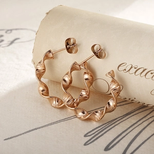 French vintage titanium steel twisted hoop earrings in rose gold on retro paper background