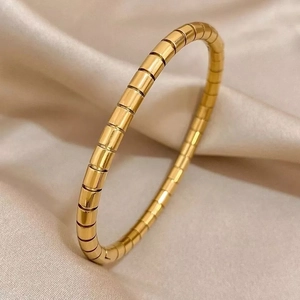 Macro detail of gold-plated bamboo joint bangle on elegant champagne silk fabric