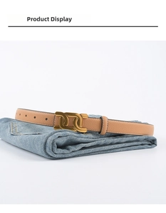 Détail de ceinture en cuir grainé camel avec boucle double anneau dorée sur jean