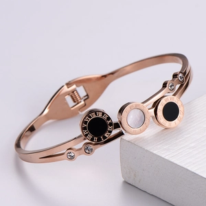 Detail of rose gold bangle featuring Roman numerals and black and white shell inlay