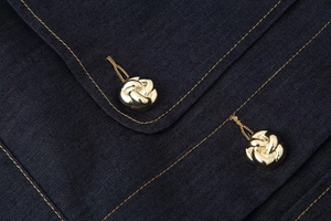 Gros plan de boutons métalliques dorés en forme de pétale sur tissu bleu marine chic