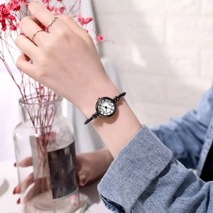 Close-up of minimalist quartz watch with white dial and black strap on female wrist