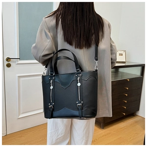 Close-up of black leather tote bag with unique wave cut and double zipper detail