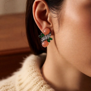 Close-up of vintage flower earrings with pink oval resin stones and green marquise crystals