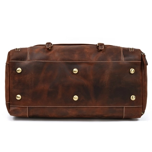 Detail view of the brown leather travel bag base with six protective gold metal rivets