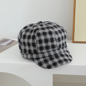 Close-up of black and grey plaid newsboy cap showing thick wool fabric texture and peak