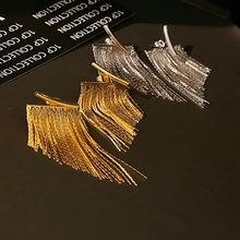 Detailed close-up of long metallic fringe tassel earrings in gold and silver finishes
