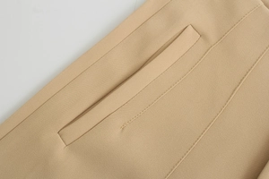 Dettaglio dei pantaloni beige che mostra le cuciture rinforzate sulla tasca e il tessuto