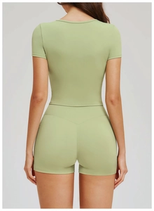 Rear view of women's light green yoga set with short sleeve crop top and biker shorts