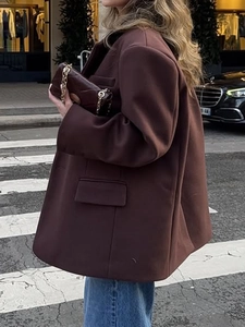 Elegant women's oversized brown long sleeve blazer styled with jeans in an urban street setting