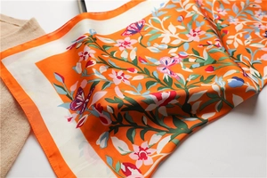 Macro detail van oranje zijden sjaal met bloemen- en vlinderpatronen op witte achtergrond
