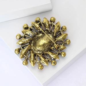Macro detail of gold flower brooch with vintage metal texture and pin-back closure
