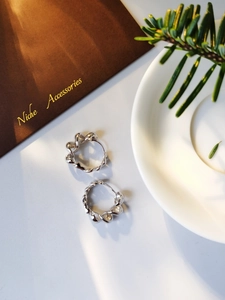 Detail of S925 silver hoop earrings featuring a twisted woven design and glossy finish