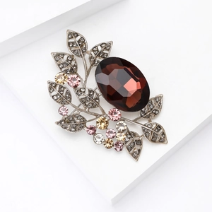 Detail of vintage oval brown gemstone brooch with colorful crystals on silver leaf branches