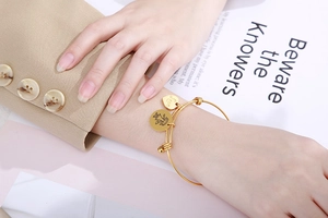 Detail of adjustable gold heart bracelet with Love charm worn by model on wrist