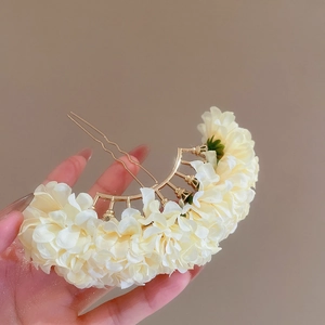Detailed close-up of cream floral hair pin with elegant gold-tone metal dual prongs