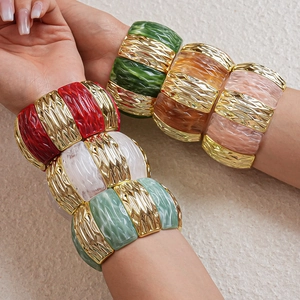 Macro view of bohemian wide acrylic bangle featuring textured metal and marbled resin inserts