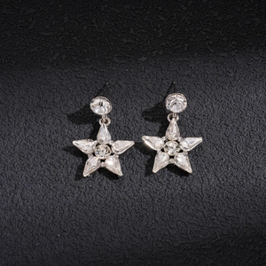 Dettaglio di orecchini a stella in argento con cristalli su sfondo nero opaco