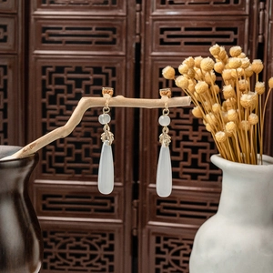 Detailed view of Chinese style long pearl tassel earrings hanging on a dry wooden branch