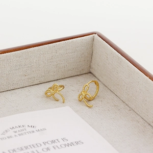 Macro shot of elegant golden bow knot earrings on a fabric-lined wooden jewelry display