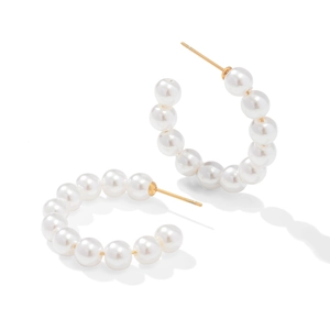 Macro shot of large white pearls set on C-shaped gold-plated stainless steel hoop earrings