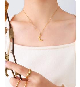 Detail of 18K gold-plated crescent moon necklace and rings worn by a model